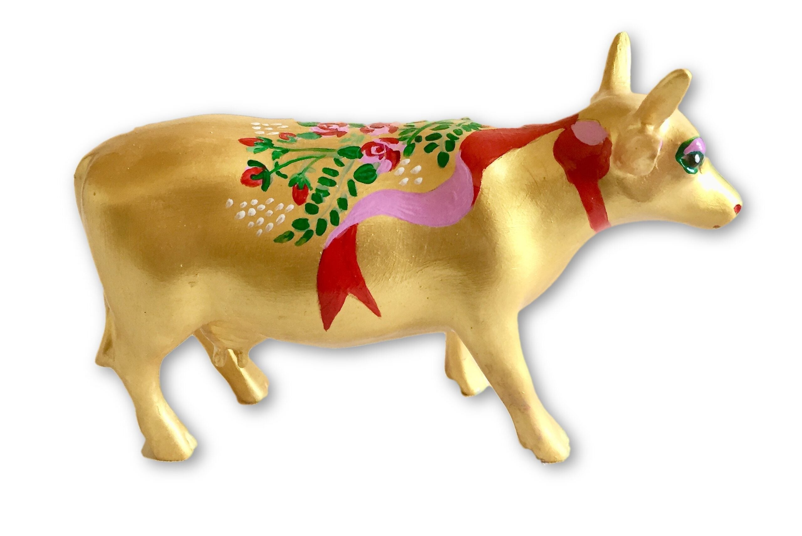 Golden resin mini cow figurine with hand-painted red and pink ribbons, floral accents, and green leaves—a collectible piece from The Painted Pigs.