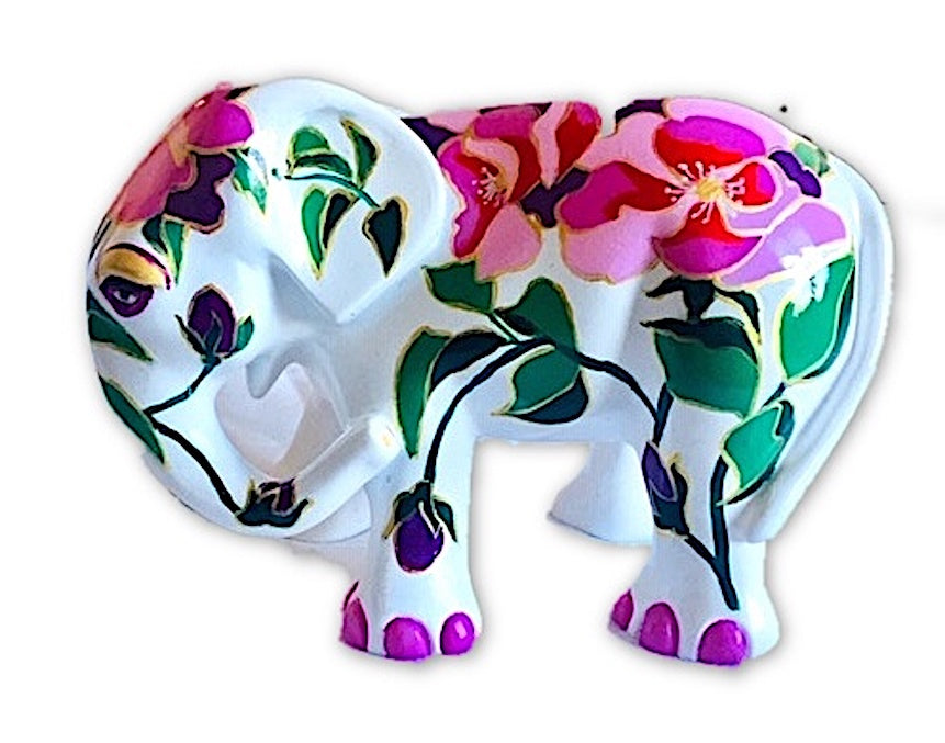Hand-painted white resin elephant figurine with bold pink, red, and purple camellia-style flowers and green leaves, part of the Painted Pigs collection