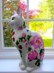 Handmade resin large cat ornament with pink peony floral design, hand-painted on white surface, displayed on windowsill with garden view in background.